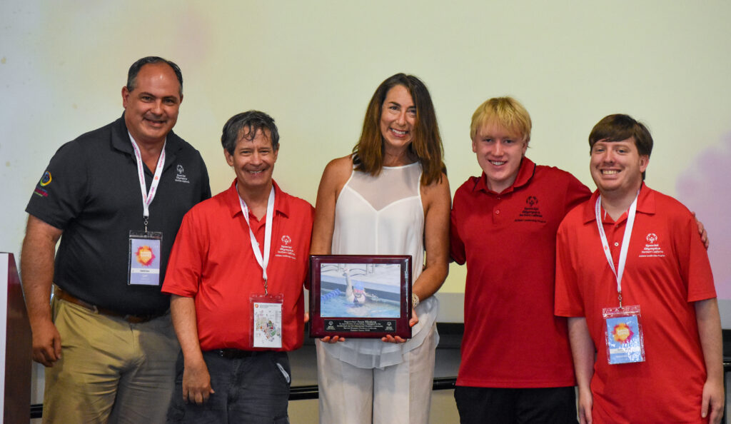 Supervisor Susan Ellenberg holds an award and stands with Special Olympics athletes and staff